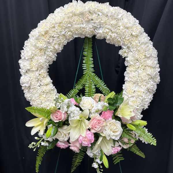 White floral funeral wreath with pink and cream flowers at the base