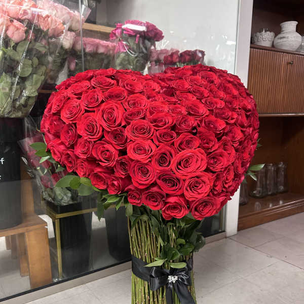 Large heart-shaped bouquet of red roses tied with a black ribbon