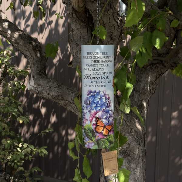 Memorial wind chime hanging from a tree with floral and butterfly artwork