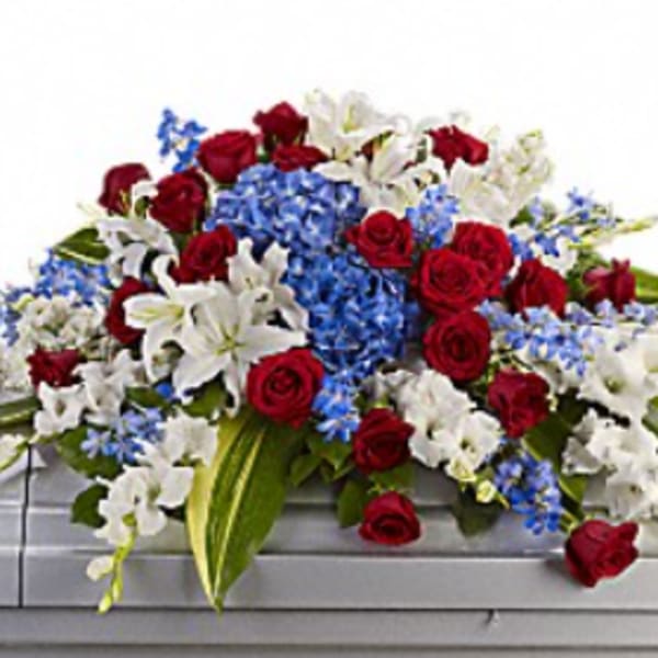 Red roses, white lilies, and blue flowers arranged on a casket