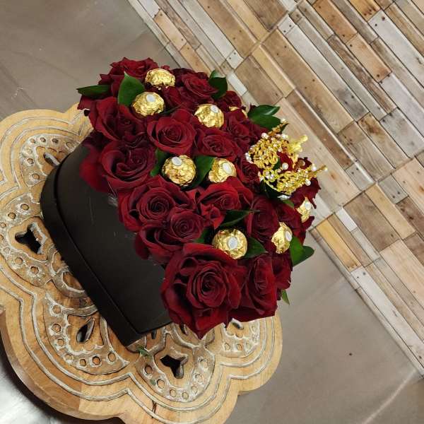 Red roses in a black box with gold chocolates and a crown topper