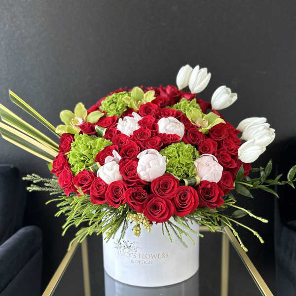 Red roses, white tulips, and green hydrangeas in a white hat box