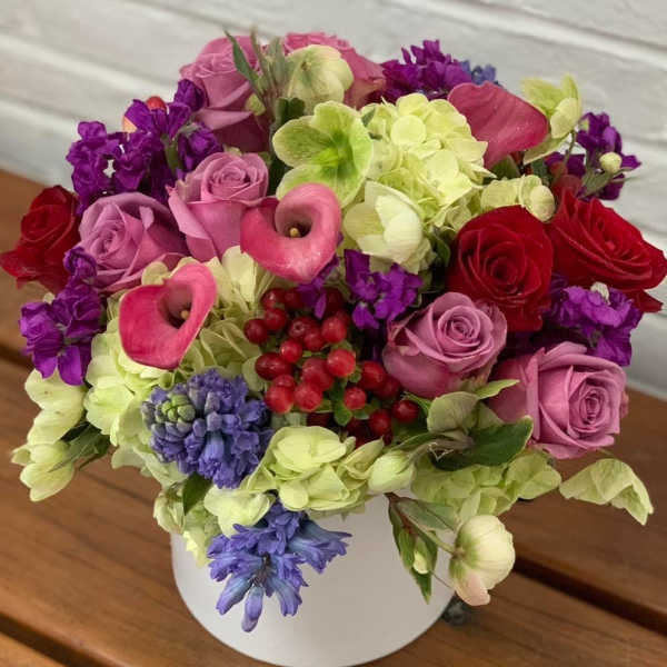 Mixed bouquet of pink roses, calla lilies, and hydrangeas in a white vase