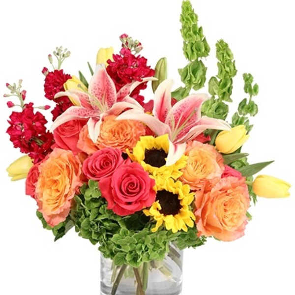 Mixed bouquet of roses, lilies, sunflowers, and tulips in a glass vase