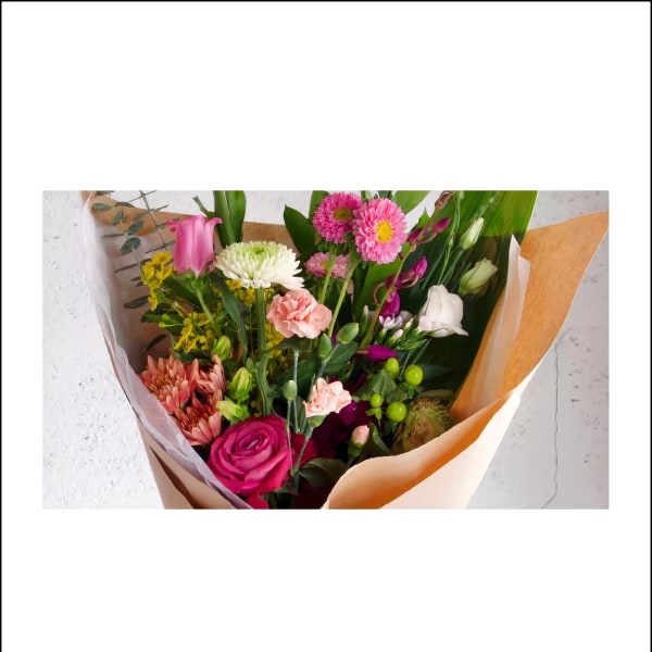 Mixed bouquet with pink roses, chrysanthemums, and carnations wrapped in paper