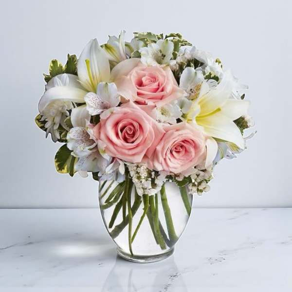 Pink roses and white lilies arranged in a clear glass vase