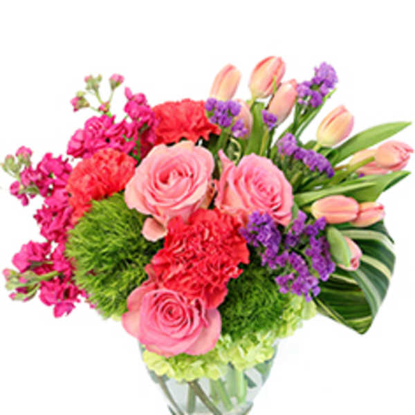 Pink roses, tulips, carnations, and purple filler in a glass vase