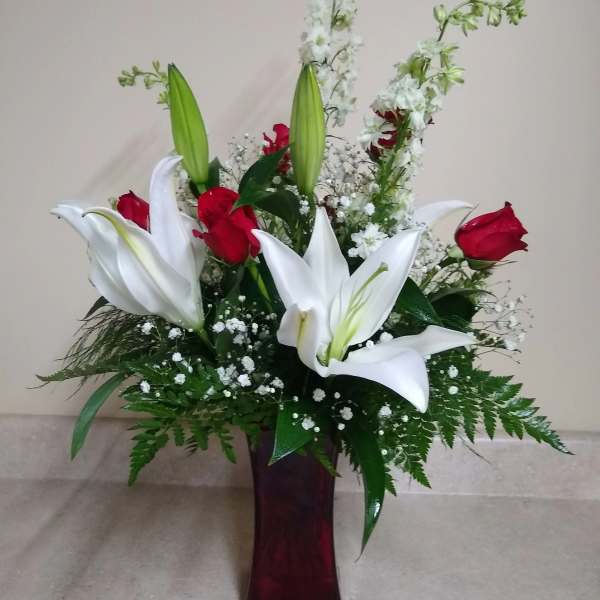 White lilies and red roses arranged in a tall vase