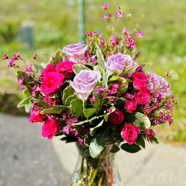 Pink and lavender roses arranged in a clear glass vase