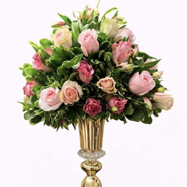 Pink and cream roses arranged in a tall gold vase