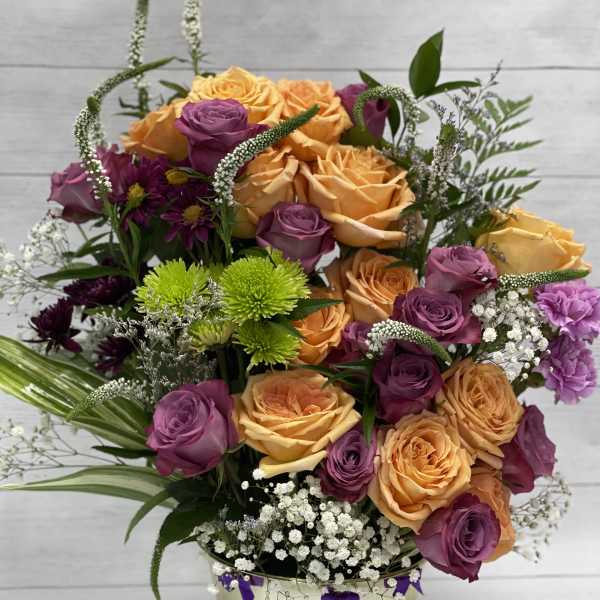 Bouquet of orange and purple roses in a gold vase