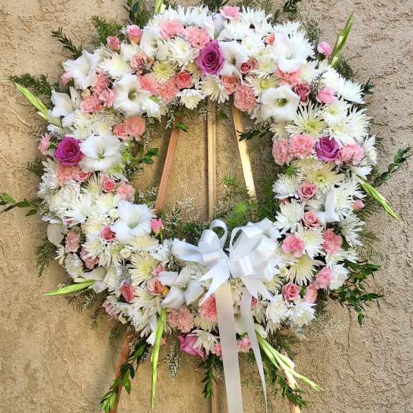 Heart-shaped floral wreath with pink and white flowers on a wooden stand