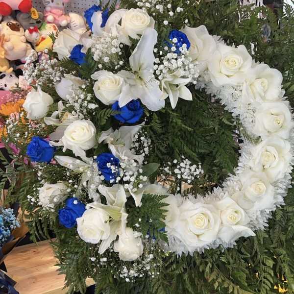 Large floral wreath of white roses, lilies, and blue roses