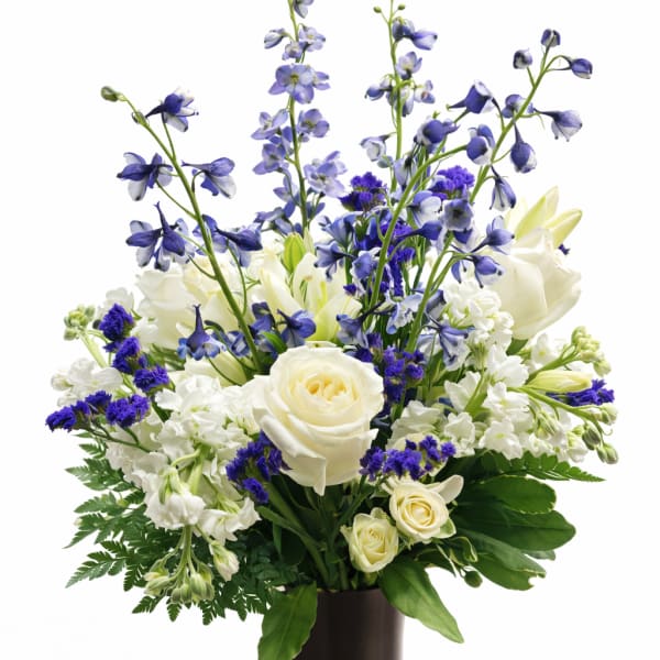 White and blue floral arrangement in a dark vase