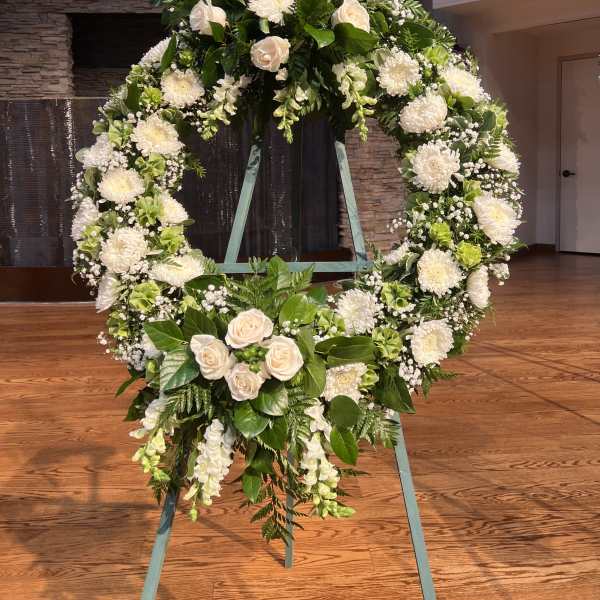 Large white floral wreath on a stand with roses and chrysanthemums