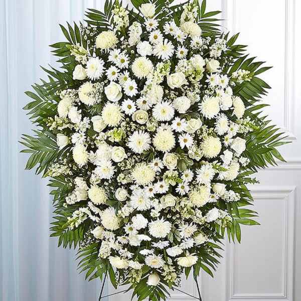 Large white funeral spray with daisies and roses on a stand