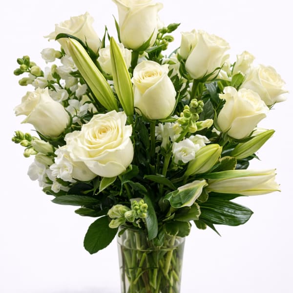 White roses and lilies arranged in a clear glass vase