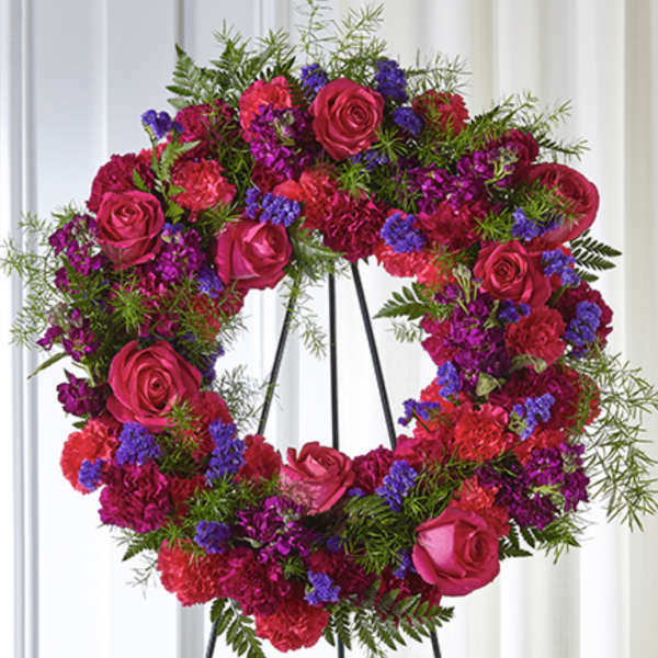 Bright pink and purple standing wreath of roses and carnations on a black metal easel