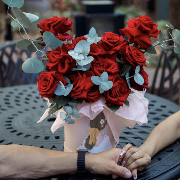 Bouquet of red roses with pale blue eucalyptus in a pink hatbox