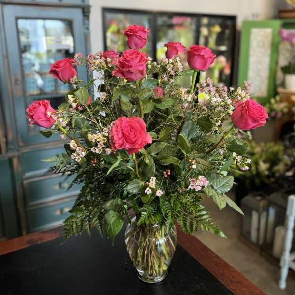 Pink roses arranged in a clear glass vase with small filler flowers