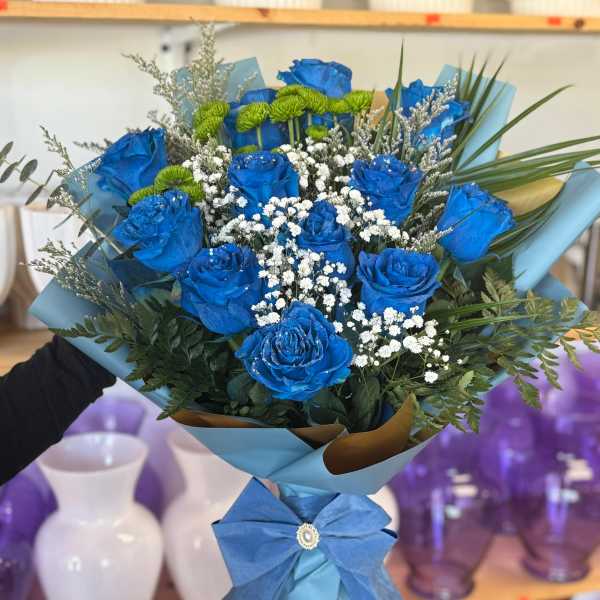 Blue roses with white baby's breath in a wrapped bouquet