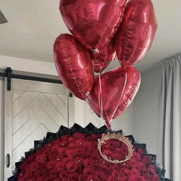 Heart-shaped rose arrangement with red balloons and a pink ribbon