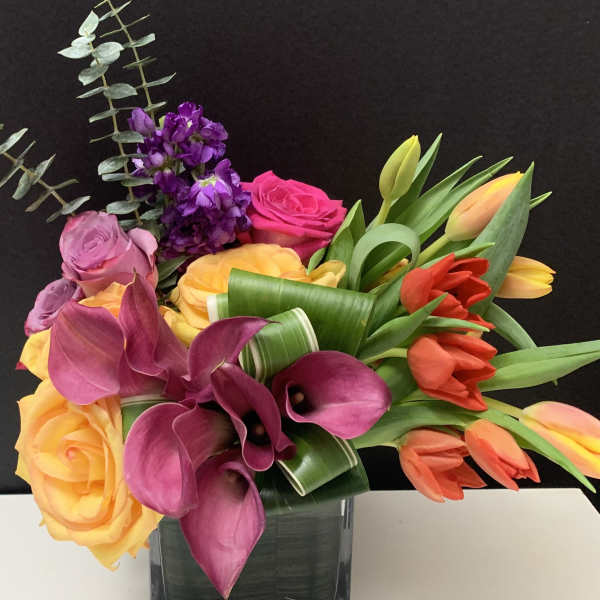 Bouquet of roses, calla lilies, and tulips in a glass vase