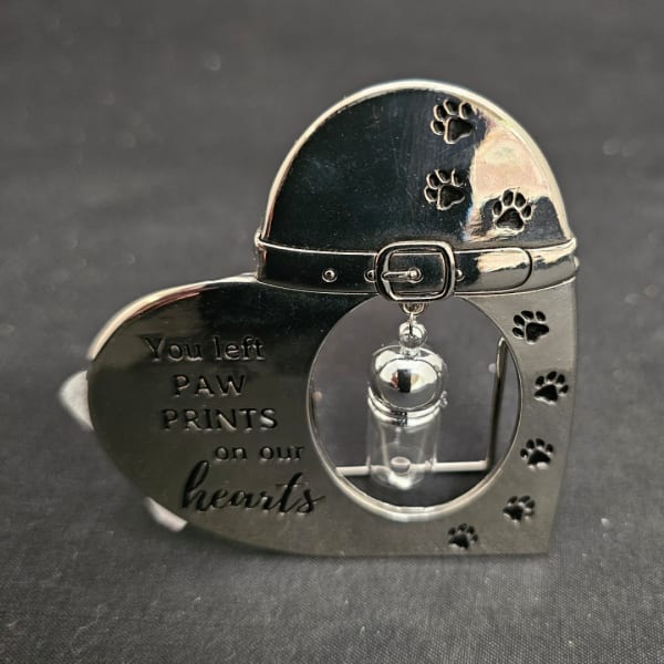 Heart-shaped memorial keepsake with paw prints and a small vial