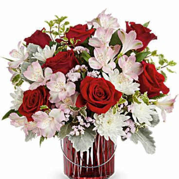 Red roses and pale pink flowers in a red glass vase