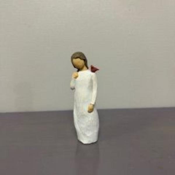 Small angel figurine in a white robe holding a red flower