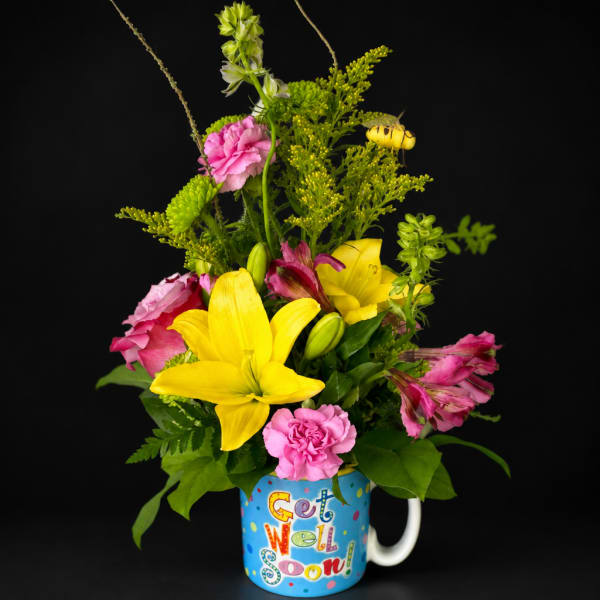 Yellow lilies and pink flowers in a mug that says Get Well Soon