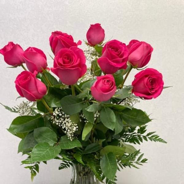 Pink roses arranged in a clear glass vase with greenery