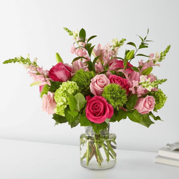 Pink roses and lilies arranged in a clear glass vase