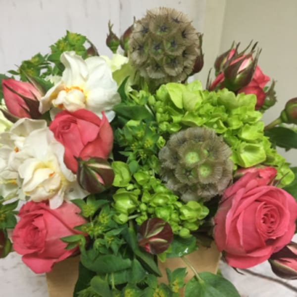 Compact arrangement of pink roses, white blooms, and green hydrangeas in a small wooden box