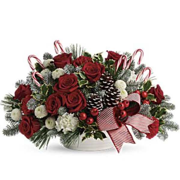 Red roses and holiday greenery in a white bowl with candy canes and ribbon