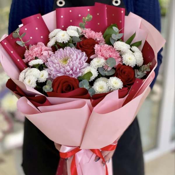 Bouquet of red roses, pink and white chrysanthemums, wrapped in pink paper