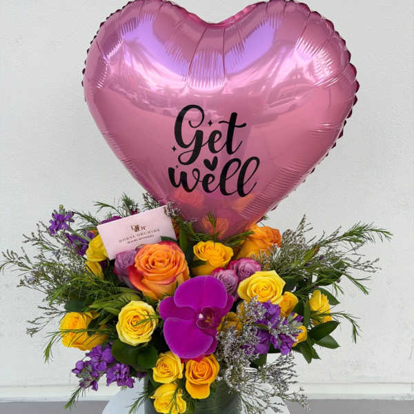 Pink heart balloon above a colorful rose bouquet in a vase