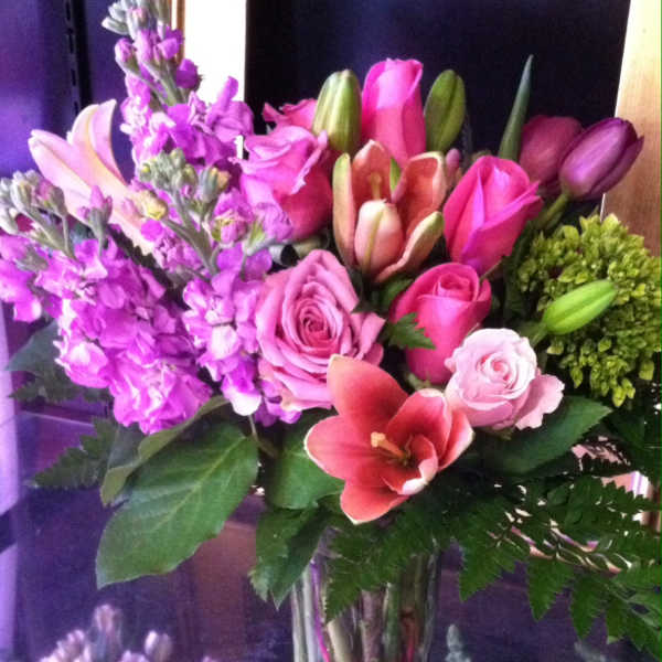 Pink and purple mixed bouquet with lilies and roses in a clear glass vase