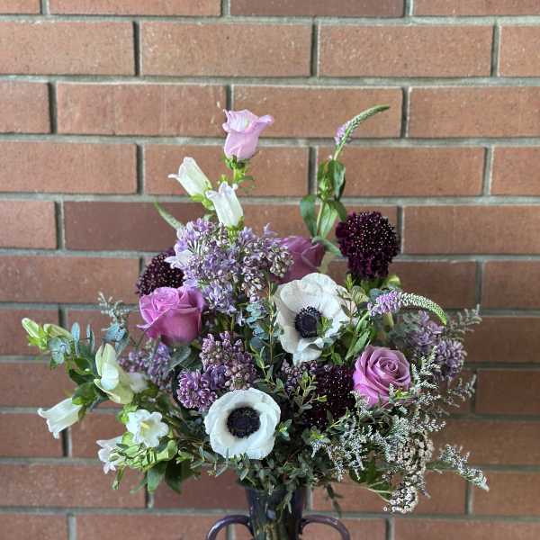 Mixed purple and white flowers arranged in a purple glass vase