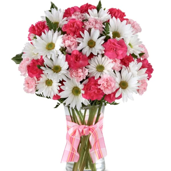 Pink carnations and white daisies in a glass vase with a pink ribbon
