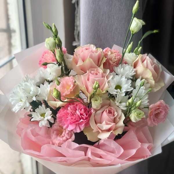 Pink and white bouquet of roses, carnations, and daisies wrapped in pink paper