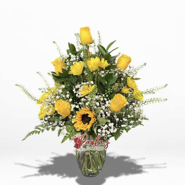 Yellow roses and a sunflower in a glass vase