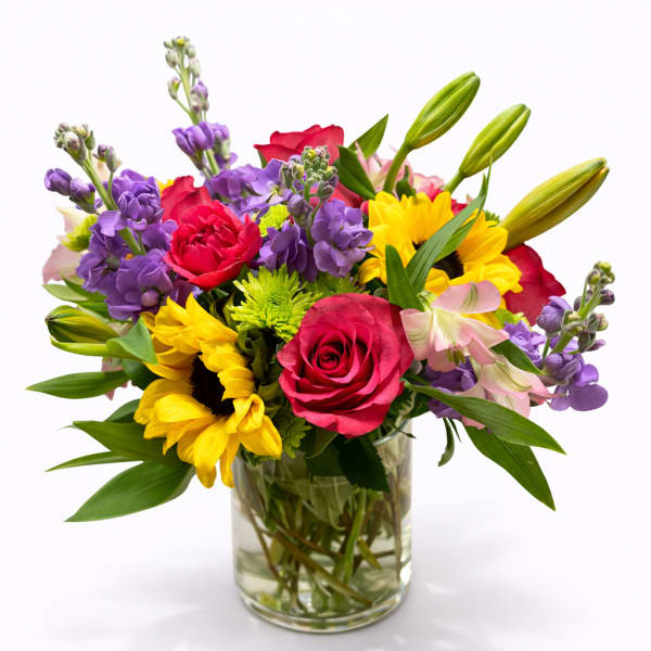 Mixed bouquet of roses, sunflowers, and lilies in a glass vase