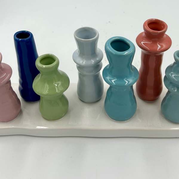 Colorful miniature ceramic vases arranged on a white tray