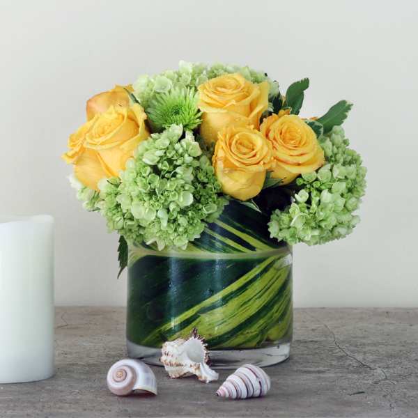 Yellow roses and green hydrangeas in a glass vase