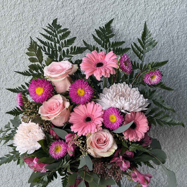 Pink roses and gerbera daisies in a purple glass vase