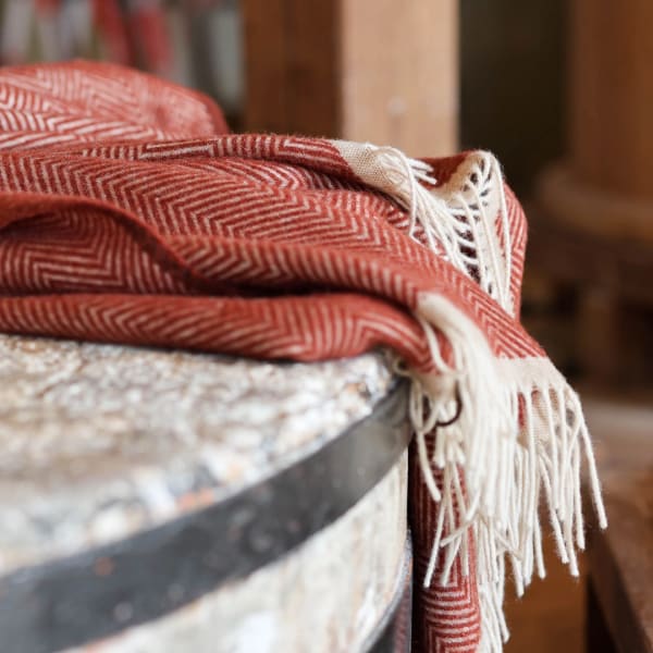 Folded red patterned throw blanket with white fringe draped over a surface