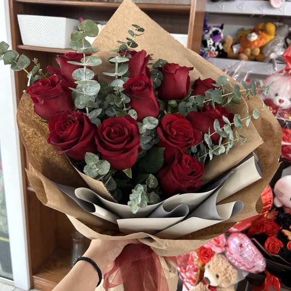 Bouquet of red roses with eucalyptus in brown paper wrap