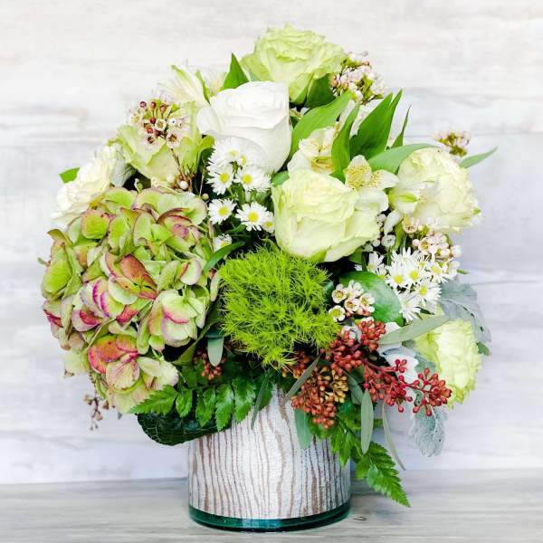 White and pale green floral arrangement in a glass vase
