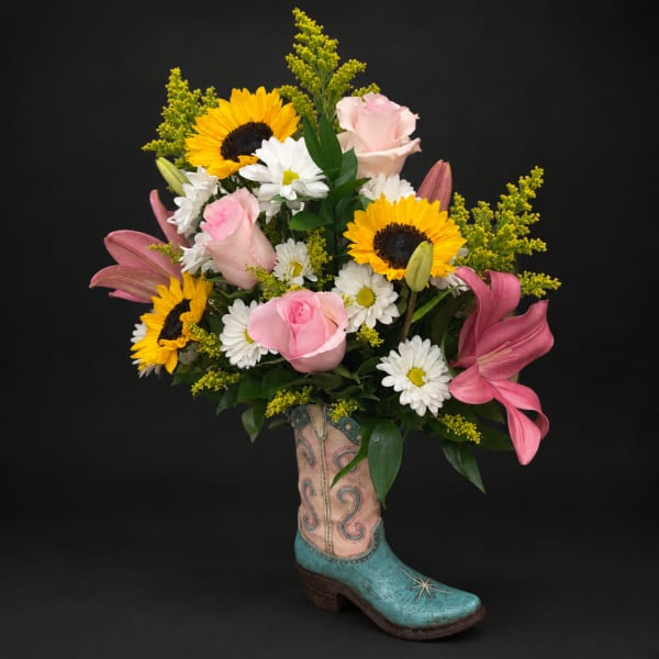 Bouquet of sunflowers, pink roses, white daisies, and lilies in a boot vase